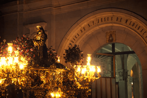 Procesión del Santísimo Cristo de Medinaceli saliendo de su Basílica durante la Semana Santa en Madrid, con el paso profusamente iluminado.